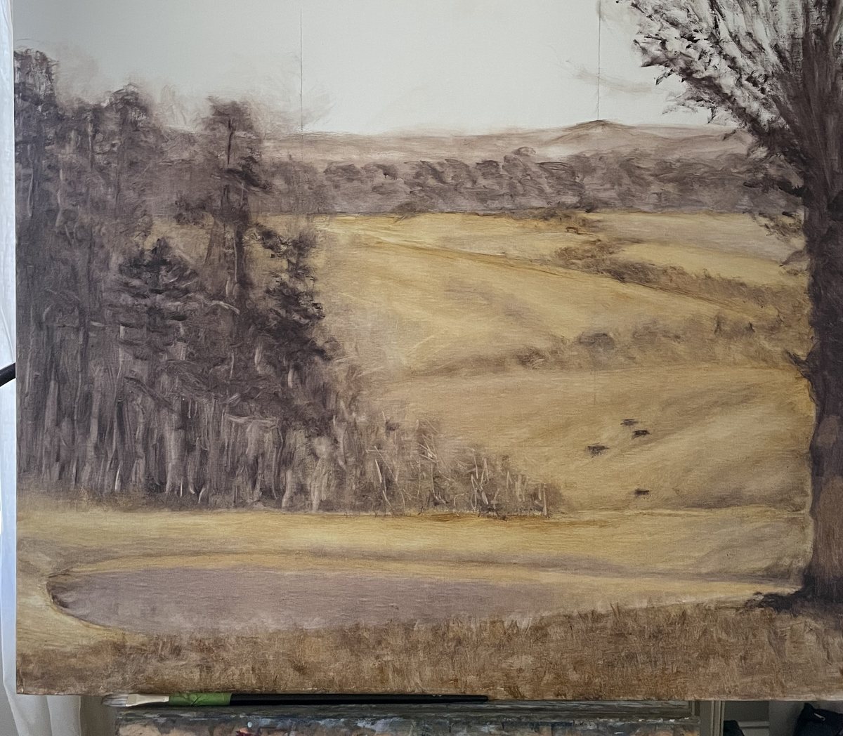 A landscape underpainting in burnt umber on the easel